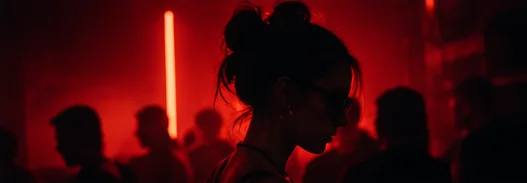 A dancer in silhouette against a red neon tube