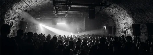 A packed railway arch with one beam of light over the crowd